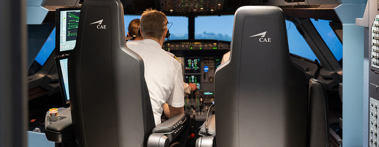 Blick in einen Cockpit-Simulator mit 2 Personen von hinten