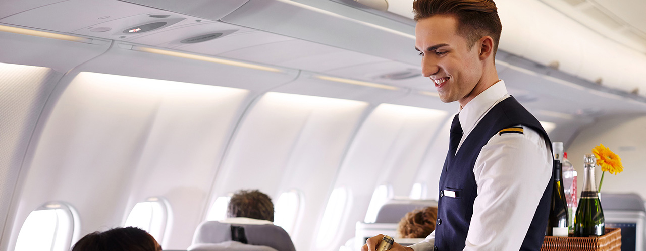 A cabin crew member presents a bottle of wine to a passenger