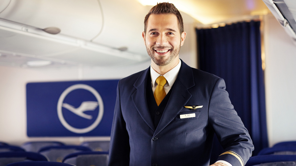 A smiling flight attendant stands in an aircraft cabin